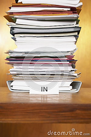 Inbox with stack of paperwork on desk Stock Photo