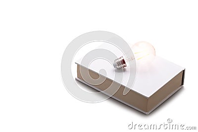 Incandescent bulbs placed on white books Stock Photo