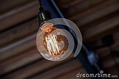 Incandescent lamps hang on the roof with blur brick wall in background. Edison lamp. Stock Photo