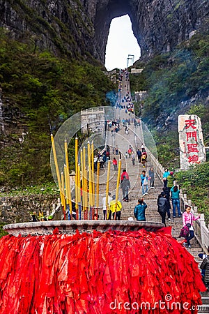 Incense pot on the bottom platform and tourists climbing 999 stairs to Haven Gate Editorial Stock Photo