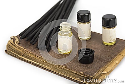 Incense sticks on a vintage book with fragrance bottles Stock Photo