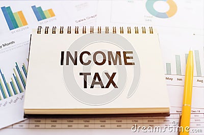 Income Tax - words notebook on financial charts. Business concept Stock Photo
