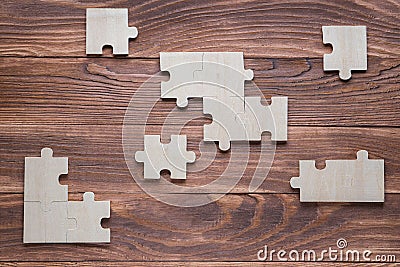 Incomplete wooden puzzles on brown wooden desk, top view, flat lay Stock Photo