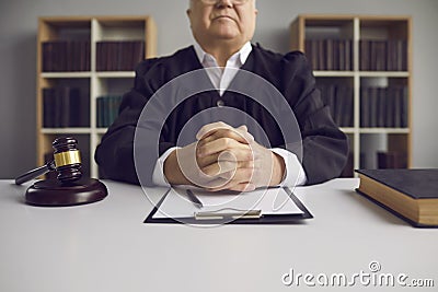 Incorruptible senior judge sitting at table with gavel and case papers in court of law Stock Photo