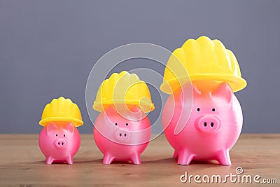 Increasing Pink Piggy Banks With Yellow Hard Hat Stock Photo