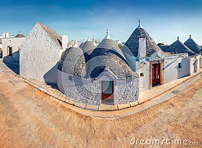 Incredible morning view of strret with trullo trulli - traditional Apulian dry stone hut with a conical roof. Sunny spring city Stock Photo