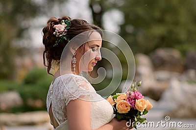 Incredibly beautiful bride with bouquet of roses. Romantic accessory of fiancee. Long haired girl in wedding gown Stock Photo