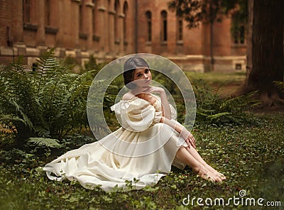 An incredibly beautiful princess sits in the castle garden amid the fern and moss. A beautifully childish face and Stock Photo