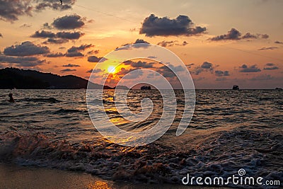 Incredibly picturesque landscape with a view of the waves in the ocean and the bronze sun at the golden hour at sunset in thailand Stock Photo