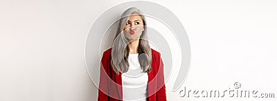 Indecisive asian businesswoman pucker lips and looking thoughtful at upper left corner, standing over white background Stock Photo