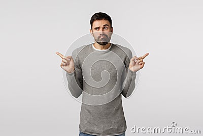 Indecisive and clueless handsome bearded guy in grey sweater, shrugging troubled make choice, have two variants Stock Photo