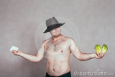 Indecisive naked corpulent man with pharmaceuticals and vegetable Stock Photo