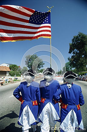 This is an Independence Day Parade with men dressed as Revolutionary War soldiers holding the American flag. It demonstrates Editorial Stock Photo