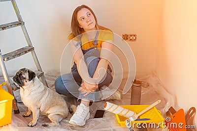 Independent young woman with pug dog planning renovation apartment sitting on floor with construction tool. diy repair Stock Photo