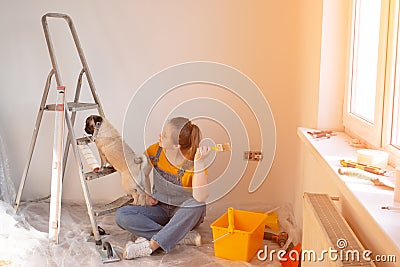 Independent young woman with pug dog planning renovation apartment sitting on floor with construction tool. diy repair Stock Photo