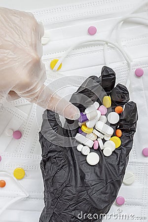Index finger points to a pile of different pills in the other gloved hand, health, treatment and medications concept Stock Photo