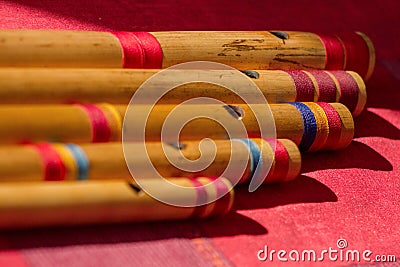 India, Comparison of different sizes of hindu bamboo flute called Bansuri on a red table. Stock Photo