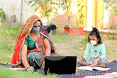 Indian rural mother teaching daughter online on laptop using internet. Stock Photo