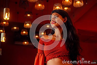 India girl long hair in red blouse stang lighting diyas in dark room Stock Photo