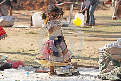 India, Hampi, 02 February 2018. A small poor and dirty Indian girl playing with sunglasses. A little girl in big glasses from the Editorial Stock Photo