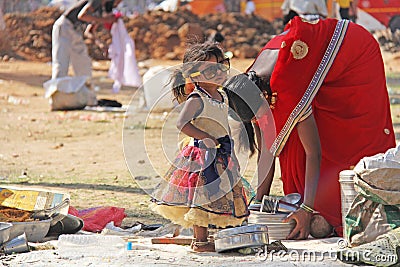 India, Hampi, 02 February 2018. A small poor and dirty Indian girl playing with sunglasses. A little girl in big glasses from the Editorial Stock Photo
