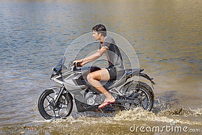 young motorcyclist rushes in the water in a spray at high speed Editorial Stock Photo