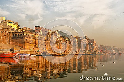 India, Varanasi Ganges river ghat with ancient city architecture as viewed from a boat on the river at sunset Editorial Stock Photo