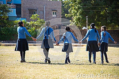 Indian asian happy school girls holding hands and walking playing in a garden wearing school uniform Editorial Stock Photo