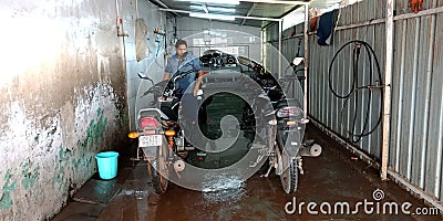 an indian automobile mechanic washing motorcycles into the bajaj service center in India Editorial Stock Photo