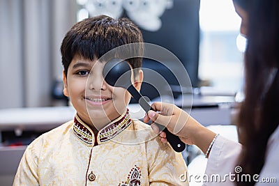 Indian boy examining eyesight checkup vision farsightedness examines ophthalmological hospital. doctor using occluder for eye Stock Photo