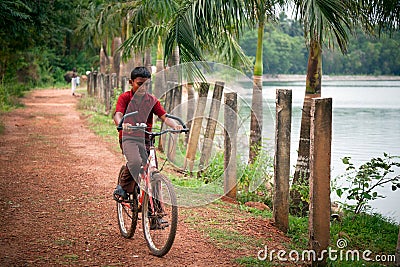 Indian boy riding bicycle near lake Editorial Stock Photo