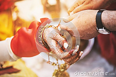 Indian bride ties with holy thread on her wrist at ceremony focus on hand with blurry background Stock Photo