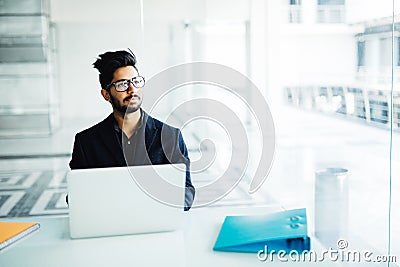 Indian Business man sitting at his desk with a laptop in office Stock Photo