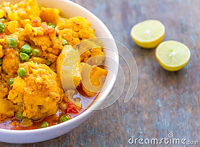 Indian Cauliflower Curry with Green Peas and Lemon Wedges Stock Photo