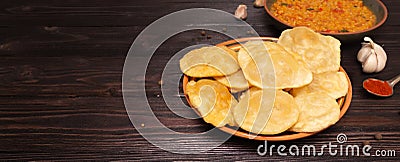 Indian cuisine. Luchi tortillas with cooked and fresh vegetables, Halwa Puri or Shira Poori. Copyspace, wood background Stock Photo