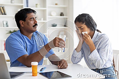 Indian doctor man comforting upset female patient crying during appointment in clinic Stock Photo