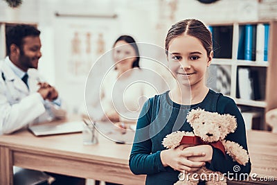 Indian doctor seeing patients in office. Daughter is posing with teddy bear. Stock Photo