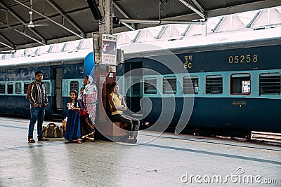 An Indian family waiting for the train on platform for traveling inside Howrah Junction railway station in Kolkata, India Editorial Stock Photo