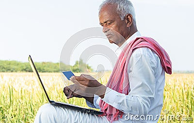 Indian farmer on laptop doing payment by using credit card - concept of rural people using technology, internet and Stock Photo