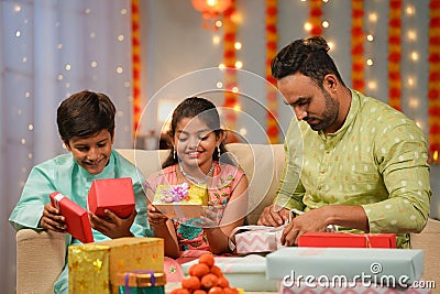 Indian father busy preparing gifts for diwali while spending time with siblings kids at home - concept of deepawali Stock Photo