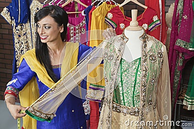Indian female dressmaker measuring traditional outfit at design studio Stock Photo
