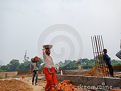 an indian female labour transporting building materials on head during construction in india dec 2019 Editorial Stock Photo