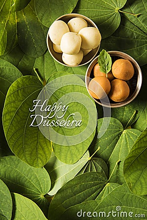 Indian festival dussehra, showing golden leaf with traditional indian sweets pedha in silver bowl on yellow background, greeting c Stock Photo