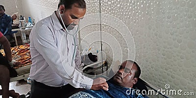 Indian government male doctor checking heart beat to the patient during treatment Editorial Stock Photo