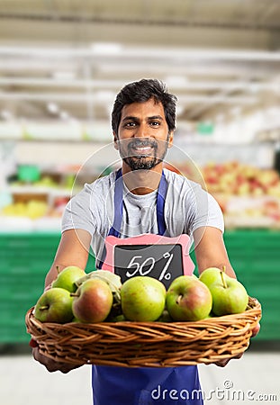 Grocery store employee offering apples from basket Stock Photo