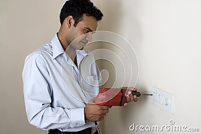 Indian man drilling hole in a wall Stock Photo