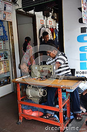 An Indian man is repairing a sewing black fabric at Little India Editorial Stock Photo