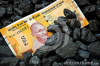 Indian money sticking out of a pile of coal, 200 rupee banknote, Concept of Mining in India, Rising coal prices, Environmental Stock Photo