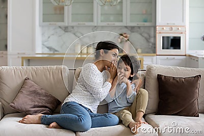 Indian mother whispering in 5s son ear, enjoying pleasant conversation Stock Photo