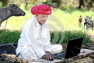 Indian old farmer smiles using laptop and internet Stock Photo